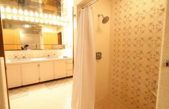 Retro-style bathroom with dual pink sinks, large mirrors, and warm vanity lighting in a Fairbanks Alaska lodge