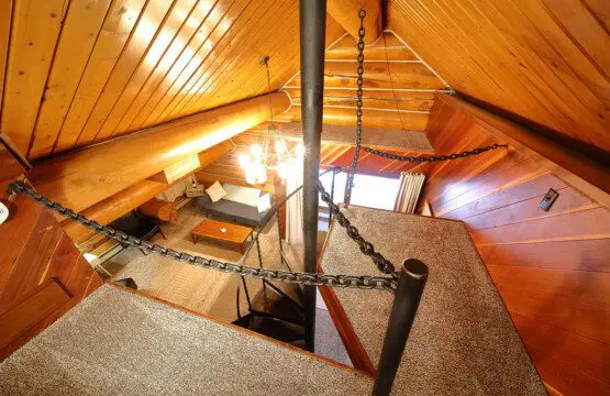 View from loft with spiral staircase and cozy living area in a wooden Fairbanks Alaska lodge