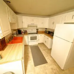 Bright white kitchen with full-size appliances, wooden countertops, and cozy cabin touches at Alaska Adventure Lodge in Fairbanks, Alaska