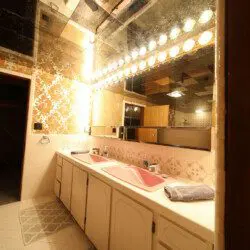 Retro-style bathroom with dual pink sinks, large mirrors, and warm vanity lighting in a Fairbanks Alaska lodge