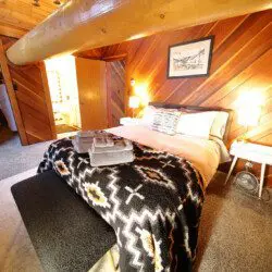 Rustic log cabin bedroom with cozy bedding and spiral staircase in Fairbanks Alaska