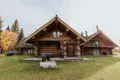 Front view of a log cabin lodge with carved bear sculpture and green lawn at Alaska Adventure Lodge in Fairbanks, Alaska