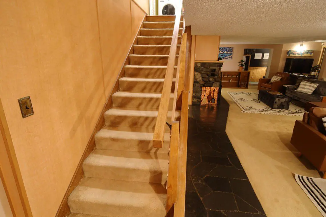 Carpeted staircase leading to upper level with laundry, overlooking cozy living space in Fairbanks Alaska lodge