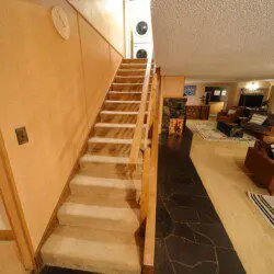 Carpeted staircase leading to upper level with laundry, overlooking cozy living space in Fairbanks Alaska lodge