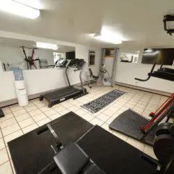 Exercise room with treadmill, weights, machines, and mirrors in a Fairbanks Alaska adventure lodge
