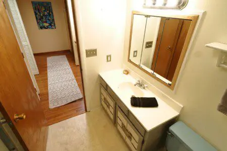 Well-lit bathroom with vanity and blue toilet in Fairbanks adventure lodge.