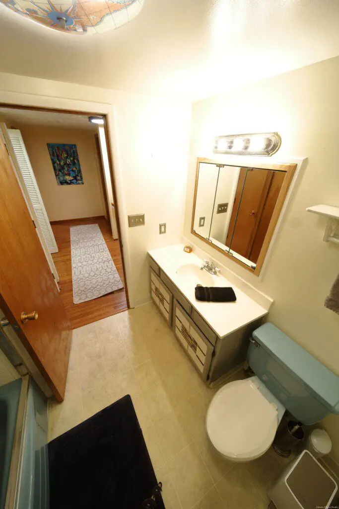 Well-lit bathroom with vanity and blue toilet in Fairbanks adventure lodge.