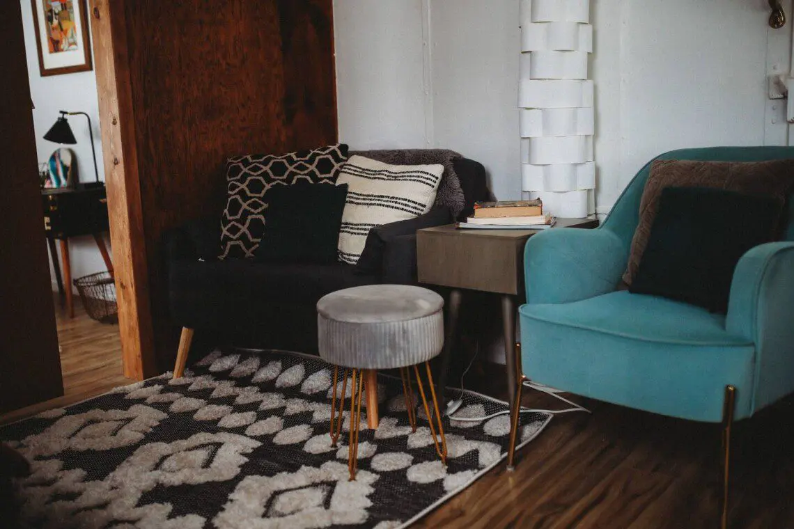 Modern seating nook with patterned pillows, teal armchair, and books in a Fairbanks Alaska treehouse rental