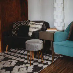 Modern seating nook with patterned pillows, teal armchair, and books in a Fairbanks Alaska treehouse rental