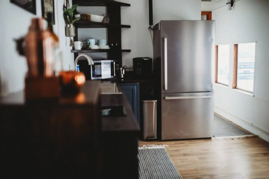 Stylish kitchen with stainless steel fridge, open shelves, and wood floors in a Fairbanks Alaska lodge