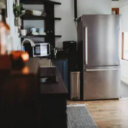 Stylish kitchen with stainless steel fridge, open shelves, and wood floors in a Fairbanks Alaska lodge
