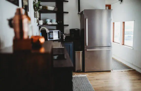 Stylish kitchen with stainless steel fridge, open shelves, and wood floors in a Fairbanks Alaska lodge