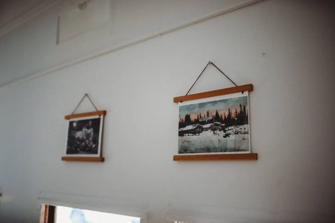 Framed historic Fairbanks prints on white wall in vintage railcar lodge.