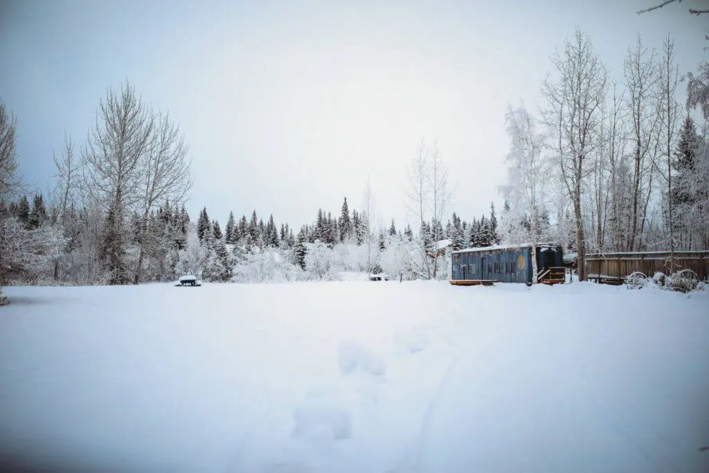 Vintage Alaska Railroad car in snowy Fairbanks forest at unique lodge stay.
