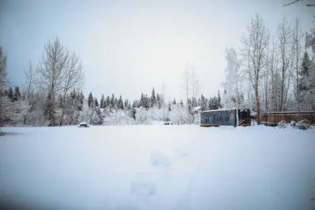 Vintage Alaska Railroad car in snowy Fairbanks forest at unique lodge stay.