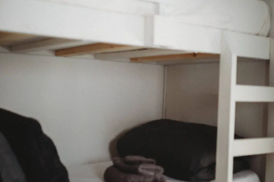 White wooden bunk beds with black pillows and folded towels in a Fairbanks Alaska adventure lodge