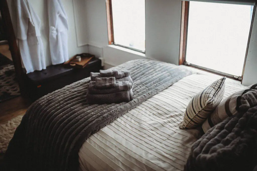 Comfortable bed with folded towels inside Alaska railroad car lodge in Fairbanks.