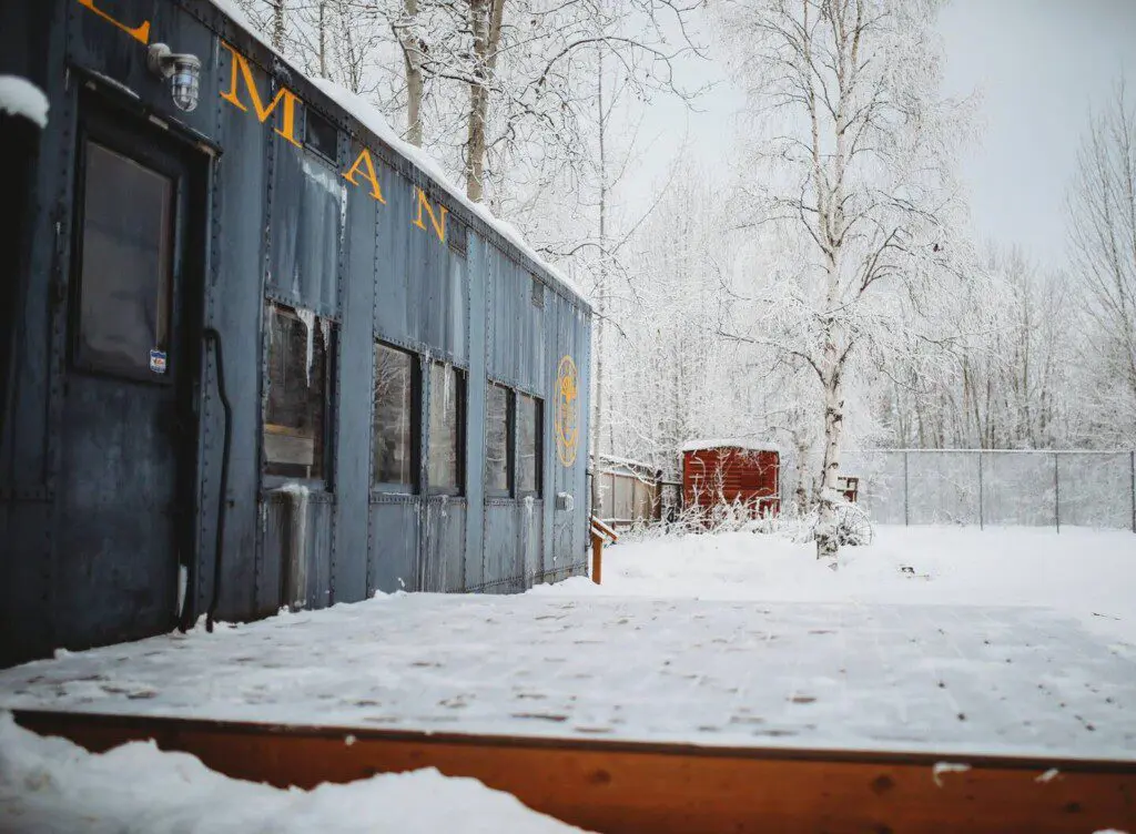 Historic railcar lodging with snowy deck and winter trees in Fairbanks Alaska