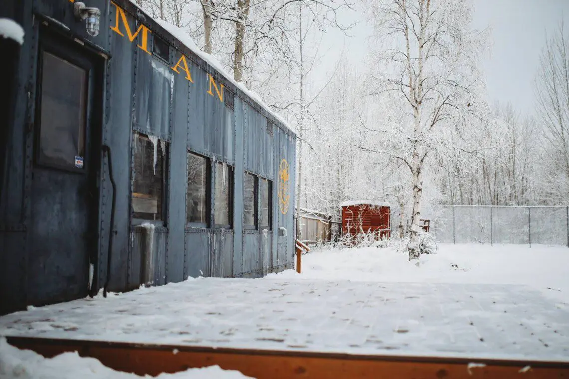 Historic railcar lodging with snowy deck and winter trees in Fairbanks Alaska
