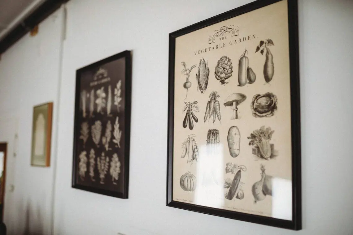 Framed vintage vegetable and herb illustrations hanging on the wall of a Fairbanks Alaska lodge