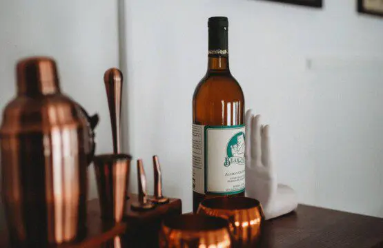 Bottle of alcohol with copper bar tools and mugs on a wooden counter in a Fairbanks Alaska lodge rental