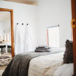 Softly lit bedroom with folded towels, white robes, and large windows in a Fairbanks Alaska lodge