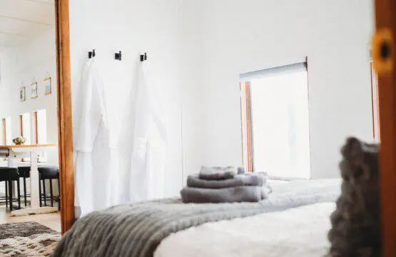 Softly lit bedroom with folded towels, white robes, and large windows in a Fairbanks Alaska lodge