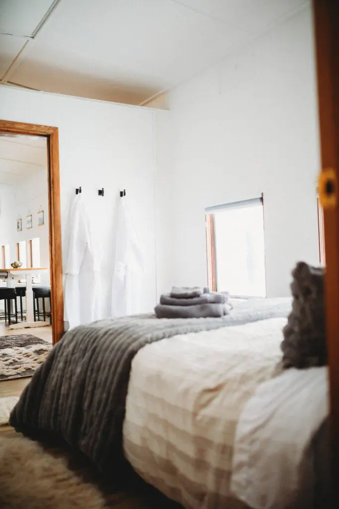 Softly lit bedroom with folded towels, white robes, and large windows in a Fairbanks Alaska lodge