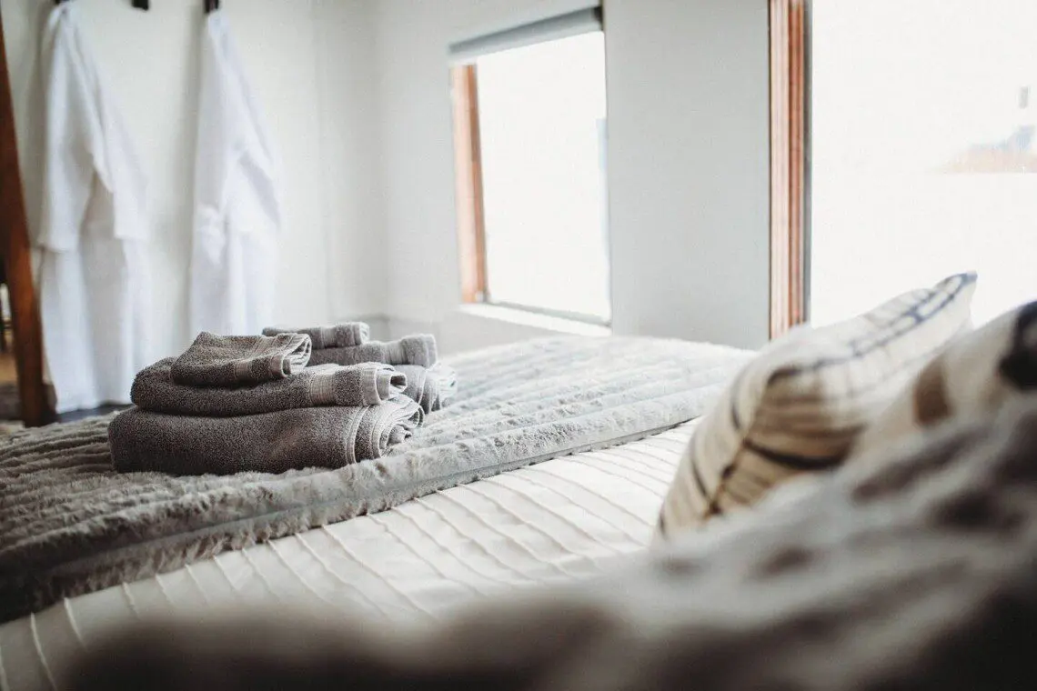 Comfortable bed with folded towels inside Alaska railroad car lodge in Fairbanks.