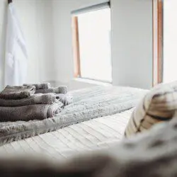 Comfortable bed with folded towels inside Alaska railroad car lodge in Fairbanks.