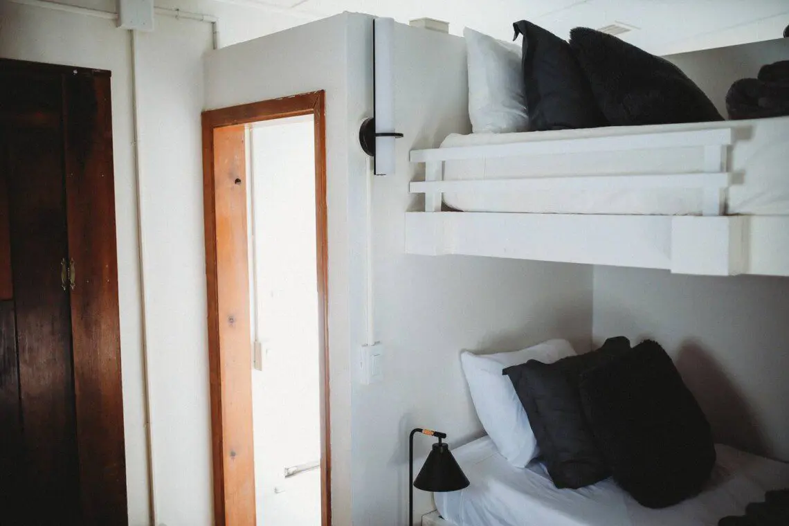 White bunk beds inside restored railcar at Alaska adventure lodge in Fairbanks.