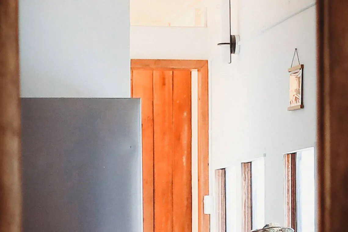 Small modern kitchen with refrigerator, bar stools, and windows in a Fairbanks Alaska lodge