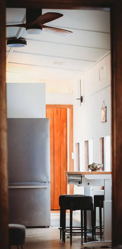 Small modern kitchen with refrigerator, bar stools, and windows in a Fairbanks Alaska lodge
