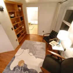 Small cozy reading corner with modern chair, lamp, and rug in a Fairbanks Alaska treehouse rental