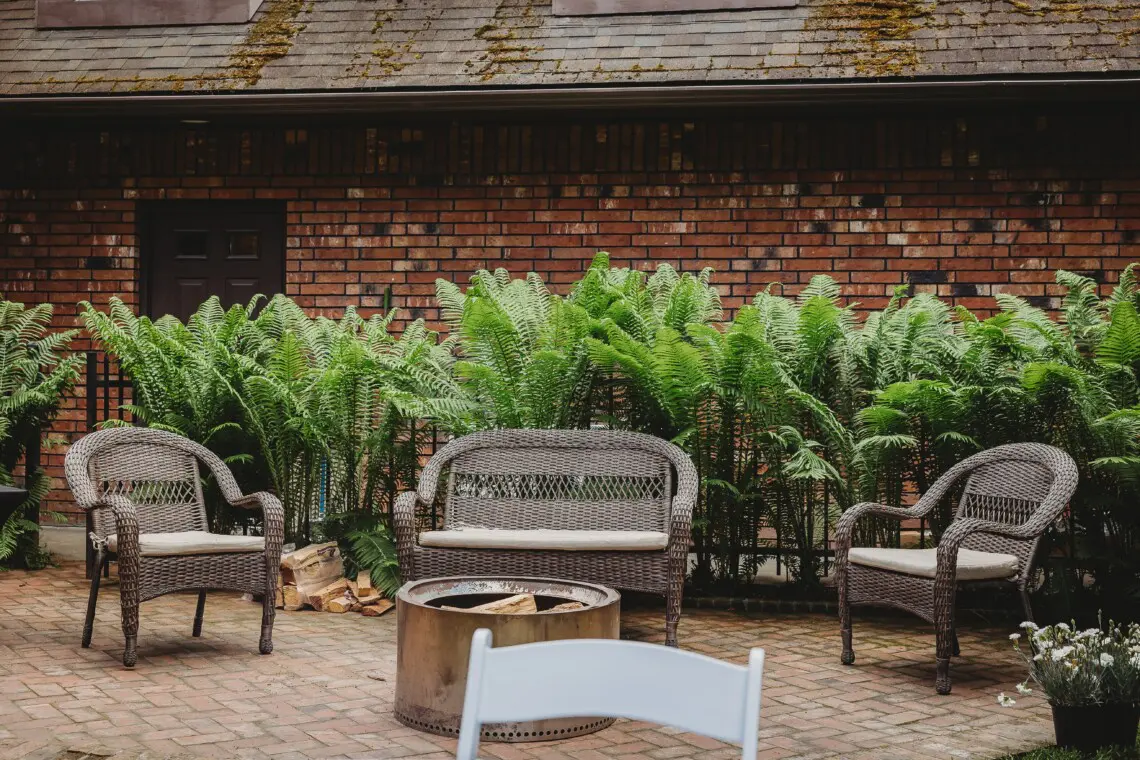 Wicker chairs and fire pit on brick patio at treehouse-style Alaska adventure lodge in Fairbanks