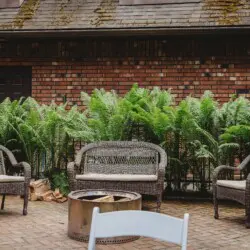 Wicker chairs and fire pit on brick patio at treehouse-style Alaska adventure lodge in Fairbanks