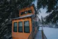 Couple standing on a snowy wooden treehouse deck surrounded by pine trees in Fairbanks Alaska