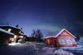 Rustic lodge and red cabin under aurora lights on Chena Pump Road in Fairbanks, Alaska.