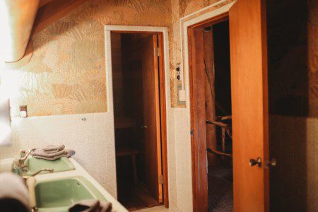 Vintage-style bathroom with green sinks and doorway leading to a private sauna in a Fairbanks Alaska treehouse
