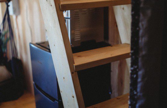 Wooden ladder above mini fridge inside a cozy treehouse rental in Fairbanks Alaska