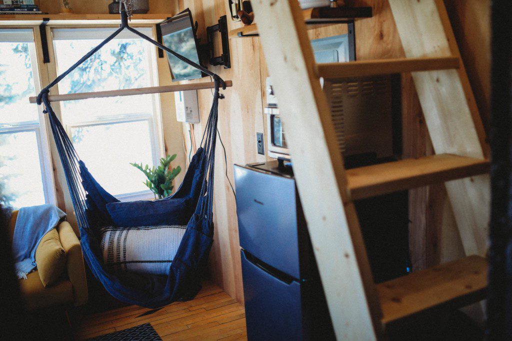 Interior view of a Fairbanks Alaska treehouse with hammock chair, mini fridge, microwave, and wooden loft ladder