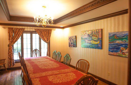Classic dining room with a long red-covered table, chandelier, wooden chairs, and wall art in a Fairbanks Alaska lodge
