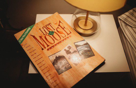 Last Frontier Moose" magazine on side table next to lamp in a Fairbanks Alaska treehouse rental