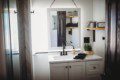 White bathroom vanity with mirror, plants, and shelves inside Fairbanks Alaska treehouse