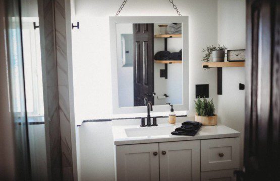 White bathroom vanity with mirror, plants, and shelves inside Fairbanks Alaska treehouse