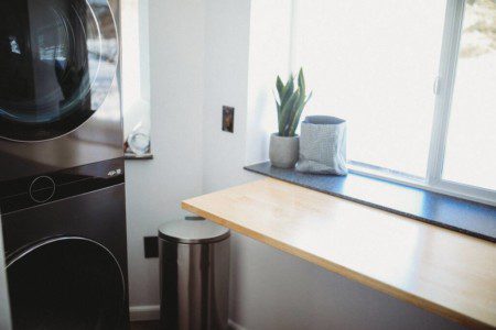 Black stacked washer and dryer in compact laundry nook of Fairbanks treehouse rental