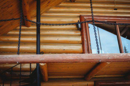 Covered log cabin deck with metal chairs and forest view reflection in Fairbanks Alaska