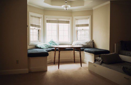Sunlit window seat with cushions and small table in a cozy Fairbanks Alaska lodge or treehouse rental