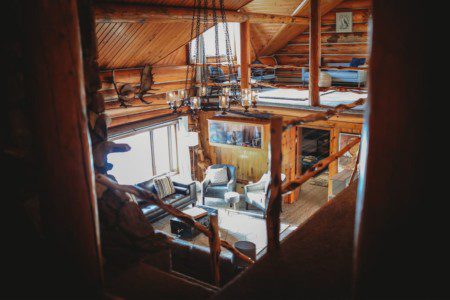 Warm wood-paneled lodge with log beams, loft seating, and cozy furniture in Fairbanks, Alaska