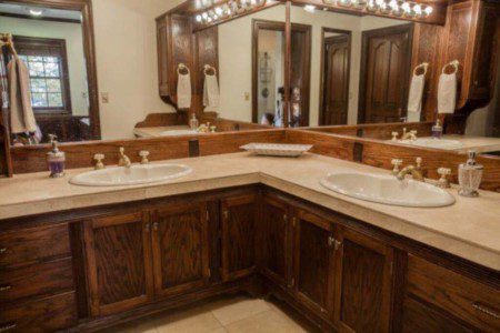 Cozy bathroom with wooden vanity, wall cross decor, and toilet in a Fairbanks Alaska lodge or treehouse rental